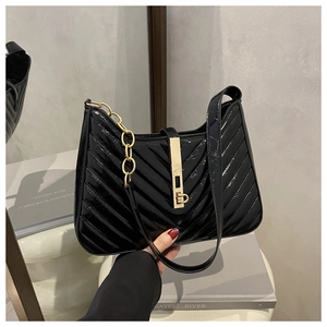 Détail du sac sous le bras en cuir verni noir avec coutures en V et chaîne dorée