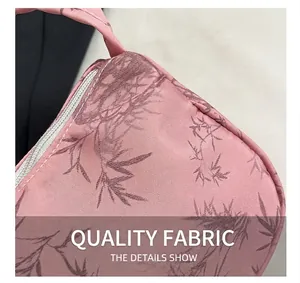 Close-up of pink fabric shoulder bag with floral print and white nylon zipper detail