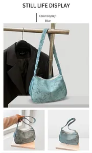 Detail of blue crescent bag featuring dark bamboo leaf patterns and shoulder strap