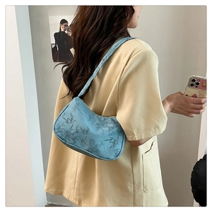 Blue underarm bag with bamboo leaf pattern shown from a side view on a model