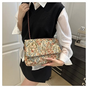 Detail of floral tapestry envelope bag featuring red blue blooms and chain strap