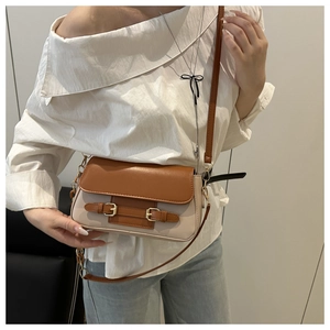 Detail showing the adjustable leather strap and gold buckle of this bicolor crossbody bag