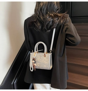 Silver metallic crossbody bag with textured finish, pearl chain, and cartoon pendant charm