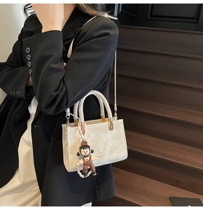 Close-up of white marble pattern leather handbag with woven handle and luxury charm detail