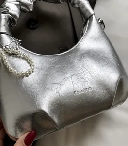 Detailed close-up of silver crescent handbag featuring pearl handle and metallic texture
