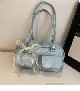 Detail of light blue faux leather handbag with cargo pockets and large white mesh bow accent