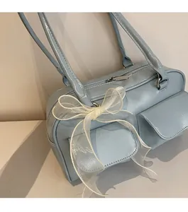 Detail of light blue soft leather Boston bag featuring a large white mesh bow decoration