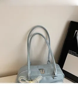 Detail of light blue glossy shoulder bag featuring dual straps and a white lace bow detail