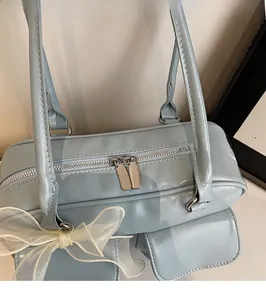 Detail of light blue PU leather bag featuring smooth dual metal zippers and lace bow accent