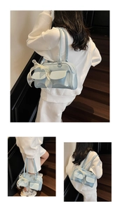 Detail of light blue soft leather bag with decorative bow and front utility pockets