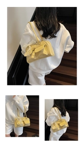 Detail of yellow glossy shoulder bag with double pockets and side mesh bow decoration