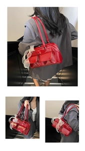 Detail of red glossy leather Boston bag with bow accents and functional front pockets