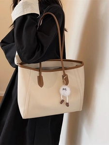 Minimalist large-capacity cream tote bag with brown trim and plush charm worn on shoulder