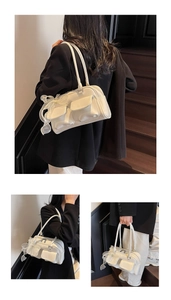 Detail of white soft leather shoulder bag featuring front pockets and lace bow accents