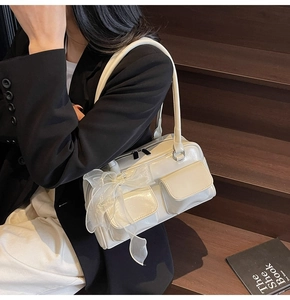 Detail of soft cream shoulder bag featuring double square pockets and organza bow accents