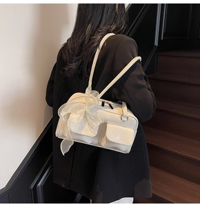 Detail of cream white shoulder bag with glossy finish and large organza bow decoration