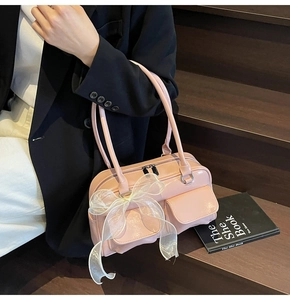Pink soft leather shoulder bag with glossy finish and organza bow detail on stairs