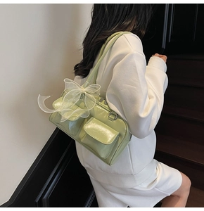 Detail view of light green glossy shoulder bag with organza bow and double straps