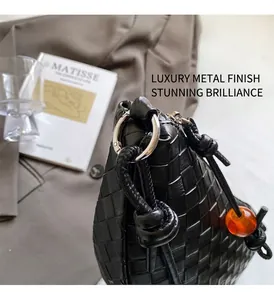 Detail of black woven leather handbag with silver ring hardware and orange bead accent