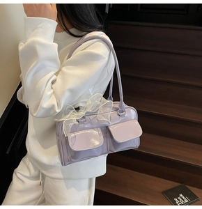 Detail view of light purple patent leather underarm bag with lace bow on model