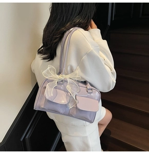 Detail of light purple glossy leather bag with white mesh bow and dual flap pockets