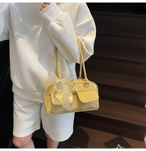 Detail of soft leather Boston bag with front pockets and a white lace bow ornament