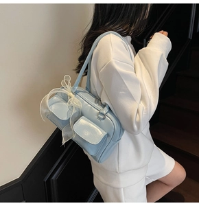 Detail of light blue patent leather bag with lace bow on model in minimalist stairs setting