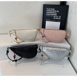 Close-up of four woven dumpling bags in beige, pink, black and silver with knot detail