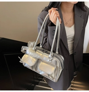 Detail of silver metallic handbag featuring front flap pockets and a tulle bow charm accessory