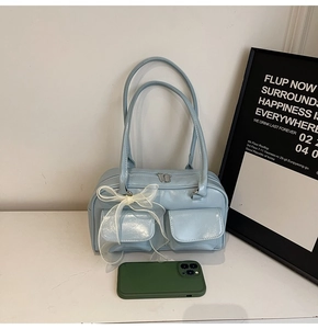 Light blue faux leather boston bag with ribbon detail shown next to a phone for size reference