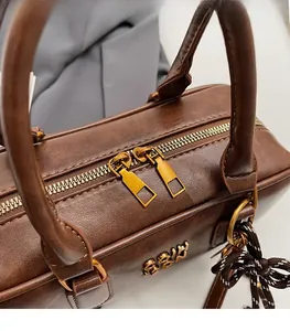 Close-up of smooth metal dual zipper and textured dark brown leather on vintage bag