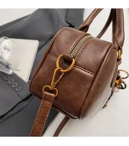 Detail of glossy gold-tone metal hardware and stitching on a vintage brown shoulder bag