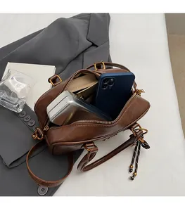 Close-up of brown leather Boston bag showing spacious interior with pockets and zipper