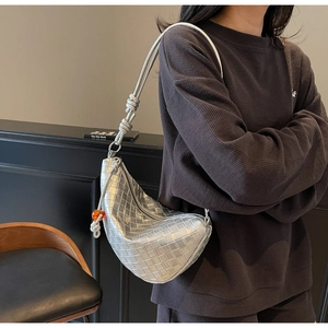Detail of silver woven leather hobo bag with a decorative knot and orange bead accent
