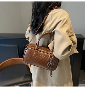 Detail of vintage brown Boston bag with gold zippers and decorative woven bow accessory
