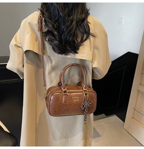 Close-up of brown vintage Boston bag featuring COIH 2DN logo and braided rope charm