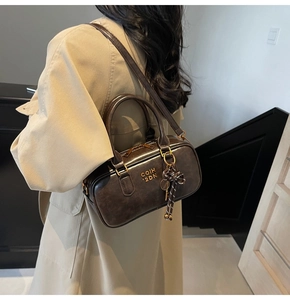Detailed view of a vintage dark brown leather boston bag with a cute bow charm