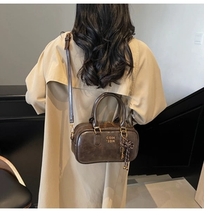 Detail of vintage brown Boston bag with gold lettering on beige trench coat outfit