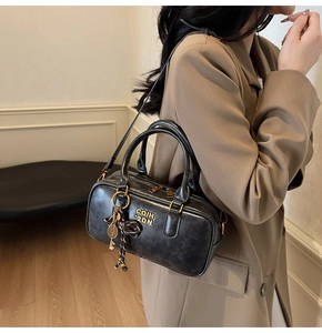 Detail of black retro leather Boston bag with gold logo and tennis racket charm