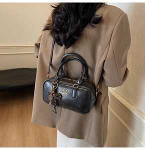 Detail of black vintage Boston bag with gold logo and tennis racket charm accessory
