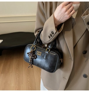 Detail of black vintage leather handbag with gold hardware and striped bow charm accessory