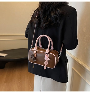 Detail of two-tone brown and pink leather boston bag showing side pendant and strap