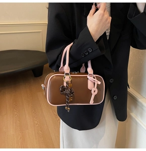 Detail of vintage bowling handbag in dark brown and pink leather with metal key charm