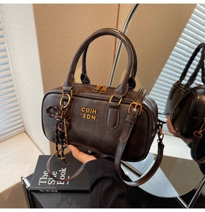 Close-up of vintage brown leather bag with gold logo and stylish key pendant decor