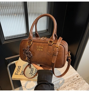 Detail of dark brown vintage texture Boston bag with gold lettering and striped ribbon