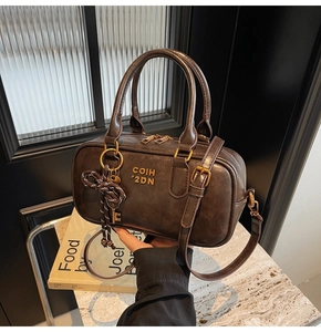 Detail of vintage brown leather Boston bag with woven bow and antique key charm