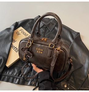 Detail of dark brown vintage Boston bag with gold logo and woven pendant decoration
