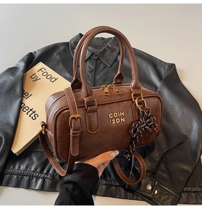 Detail of vintage brown leather Boston bag with gold logo and striped ribbon charm