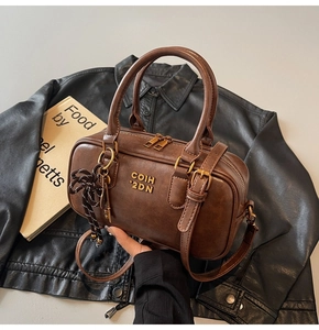 Detail of vintage brown leather boston bag with gold logo and woven rope knot accessory