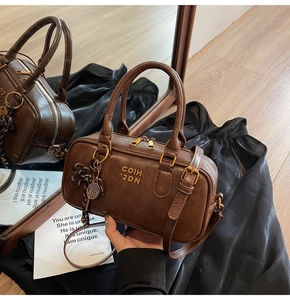 Detailed view of deep brown vintage Boston bag with gold zippers and tennis racket charm